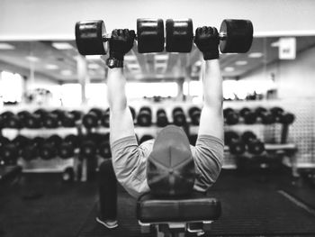 Man lifting dumbbells while exercising in gym