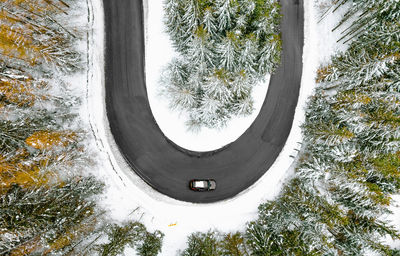Aerial view of car on winding road in winter forest