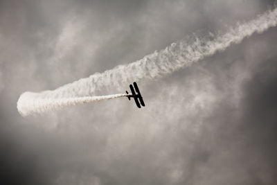 Low angle view of airplane against cloudy sky