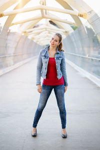 Portrait of young woman standing on footpath
