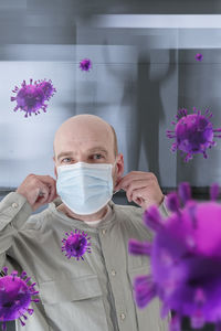 Portrait of man standing by pink flowering plants