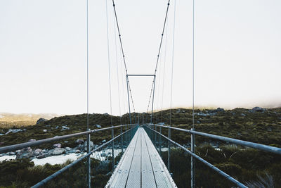 Symmetrical suspension bridge against foggy sky. hooker valley track, mount cook national park
