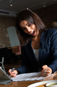 Businesswoman with mouth open reading document in restaurant