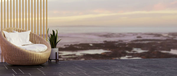 Empty chairs and table against sea during sunset