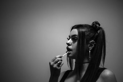 Young woman looking away while applying make-up over white background