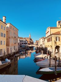 Boats in canal against clear blue sky