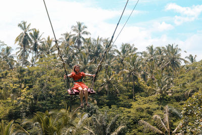 Young pretty asian woman is swinging on the cliff of the jungle in ubud, bali.