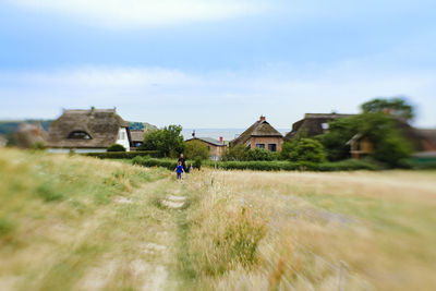 Person standing on grassy field against cloudy sky