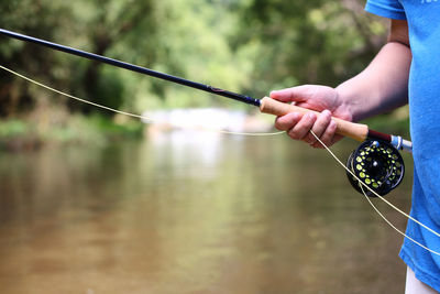 Hand holding fishing rod over water