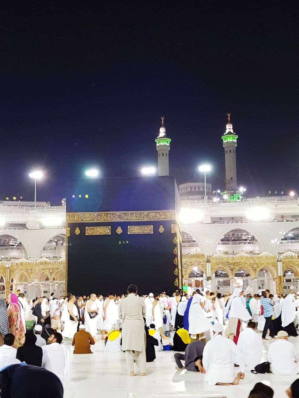 PEOPLE AT ILLUMINATED TEMPLE AGAINST SKY AT NIGHT IN CITY