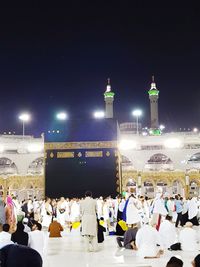 People at illuminated temple against sky at night