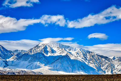 Blue sky with white clouds above snowy eastern sierra nevada mountains