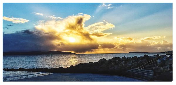 Scenic view of sea against cloudy sky at sunset