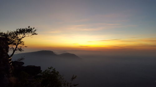 Scenic view of silhouette mountains against orange sky