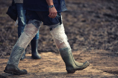 Low section of man tied polythene bag on leg while walking on footpath