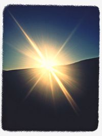 Low angle view of sun shining through clouds