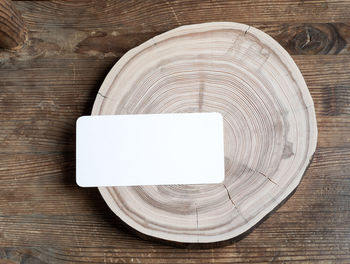 Rectangular empty paper card on wooden cross slice on old weathered rustic wooden table.copy space. 