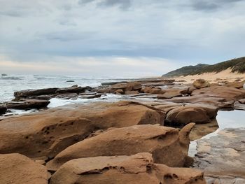 Scenic view of rocks on beach against sky