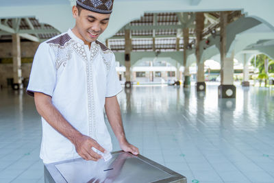 Man donating currency in donation box at mosque