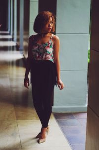 Full length of young woman standing in corridor