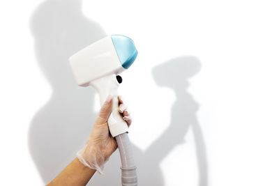 Cropped hand of woman holding dental equipment against white background