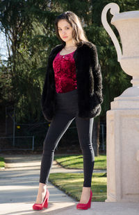 Portrait of a beautiful young woman standing against the wall