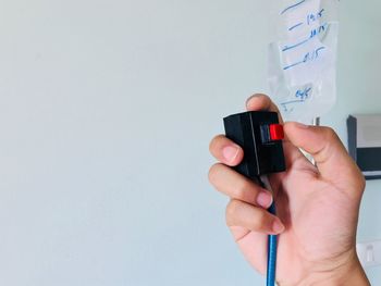 Midsection of person holding camera against wall