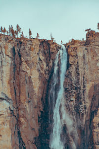 Low angle view of waterfall against clear sky