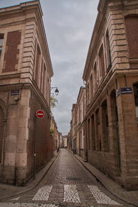 Narrow street between buildings against sky