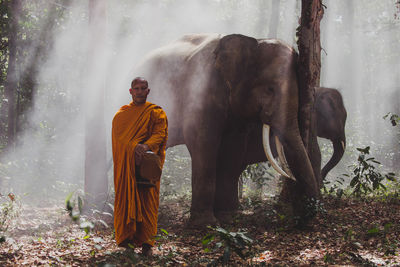 Man standing by waterfall in forest