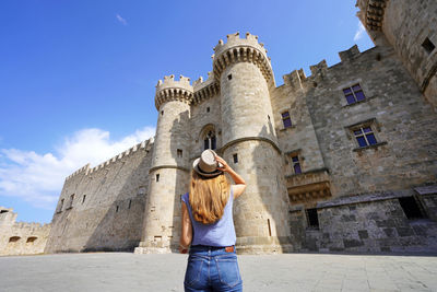 Back view of tourist girl visiting the palace of the grand master of the knights of rhodes, greece