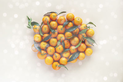 Bright mandarines with leaves on the beige background