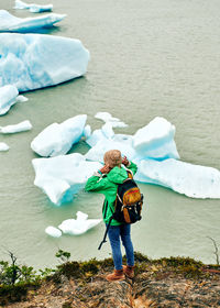 High angle view of woman standing overlooking icebergs at lago grey in patagonia, chile