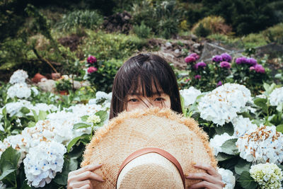 Portrait of woman with pink flowers against plants