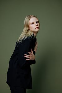 Portrait of young woman standing against wall