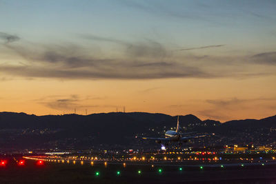 Illuminated city against sky at sunset