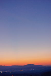 Scenic view of silhouette mountains against clear sky during sunset