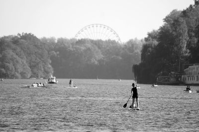 Rear view of woman paddleboarding in sea 