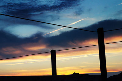 Low angle view of silhouette cables against sky