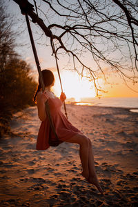 Woman on beach against sky during sunset