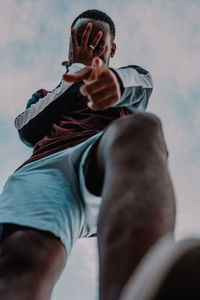 Low angle view of man holding hands against sky