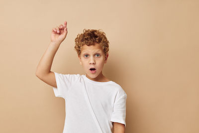 Portrait of boy gesturing against beige background