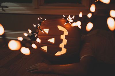 Man with jack o lantern and lighting equipment resting at home during halloween