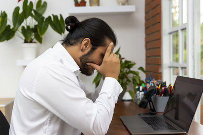 Side view of young man using mobile phone while sitting on table