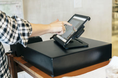 Cropped hand of customer making payment over tablet computer at store