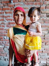 Portrait of mother and daughter against wall