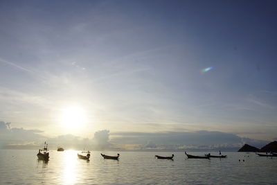 Boats in sea at sunset