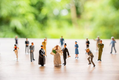 Close-up of figurines on wooden table against trees