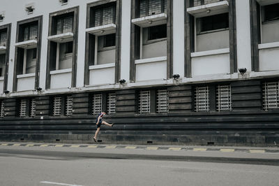 Side view of woman walking on footpath in city