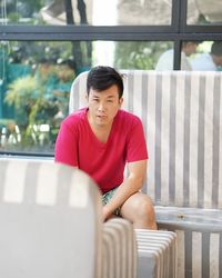 Portrait of mid adult man sticking out tongue while sitting on bench